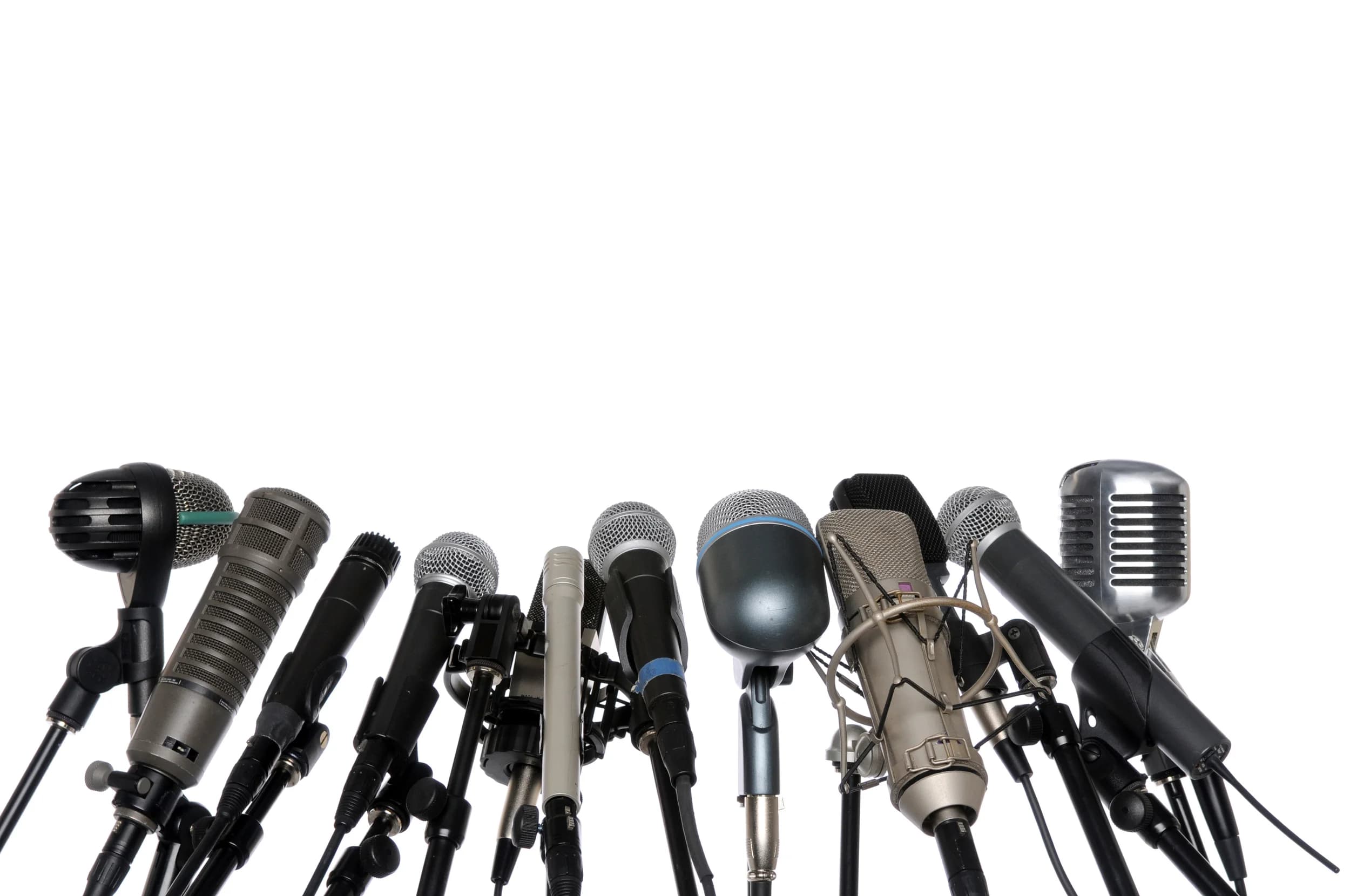 A row of press microphones on stands, massed as at a news conference.