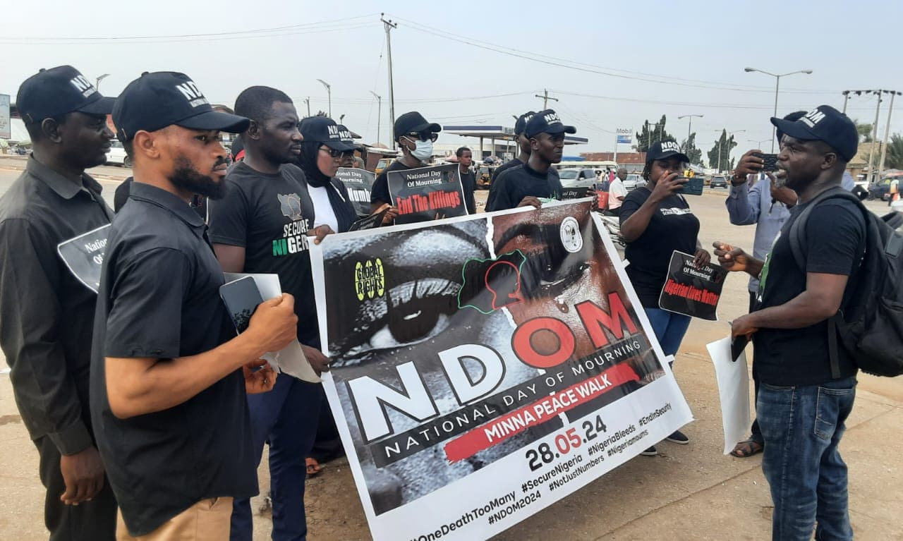 Campaigners at a National Day of Mourning peace walk in Minna, holding a banner and placards calling for an end to the killings.